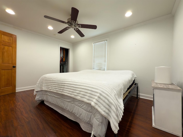 bedroom featuring a spacious closet, dark hardwood / wood-style flooring, a closet, ceiling fan, and crown molding