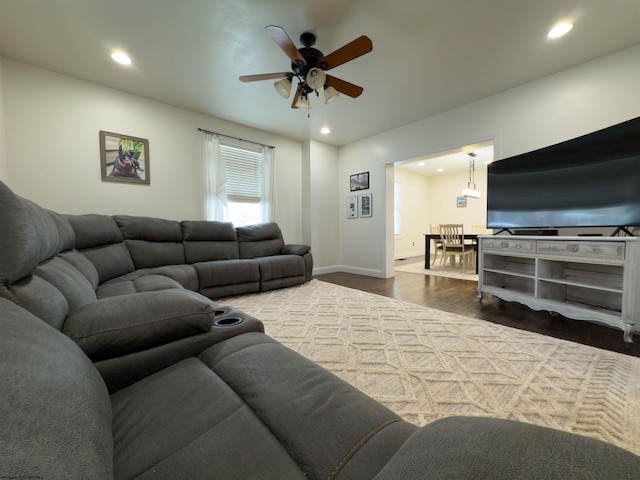 living room featuring ceiling fan and dark wood-type flooring