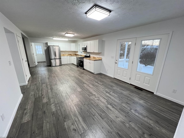 kitchen with a textured ceiling, dark hardwood / wood-style flooring, stainless steel appliances, and white cabinetry