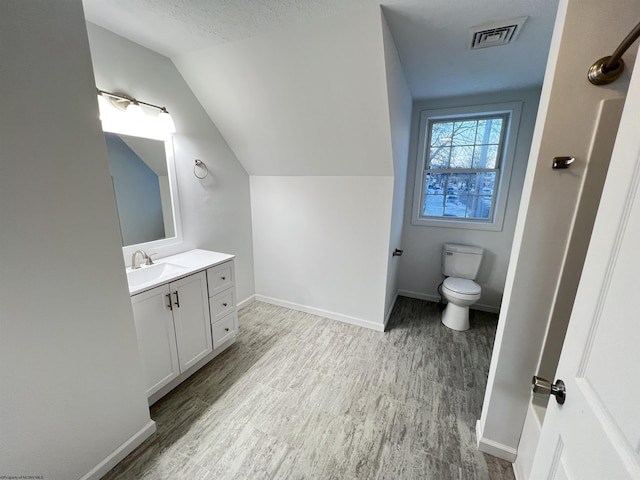 bathroom featuring a textured ceiling, toilet, vanity, and lofted ceiling