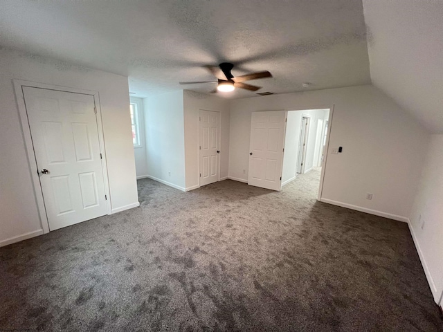 additional living space featuring a textured ceiling, ceiling fan, lofted ceiling, and dark colored carpet