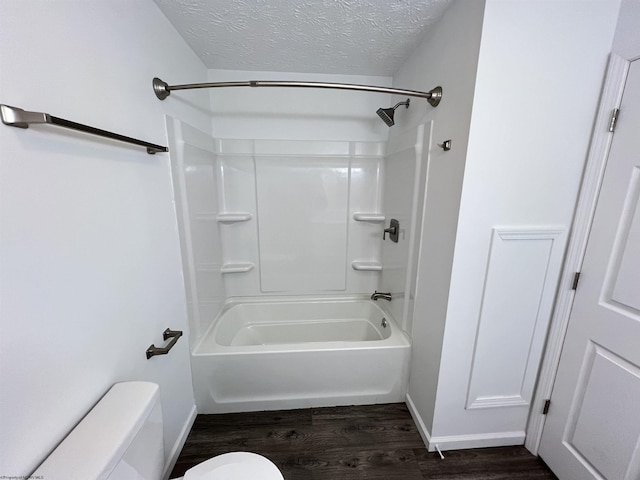 bathroom featuring hardwood / wood-style flooring, bathtub / shower combination, a textured ceiling, and toilet