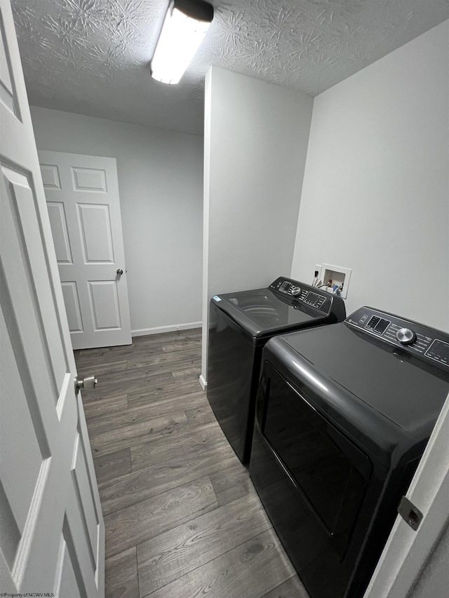 clothes washing area featuring a textured ceiling, independent washer and dryer, and dark hardwood / wood-style floors