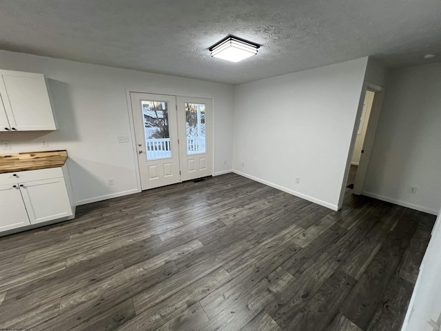 unfurnished dining area with a textured ceiling and dark hardwood / wood-style floors