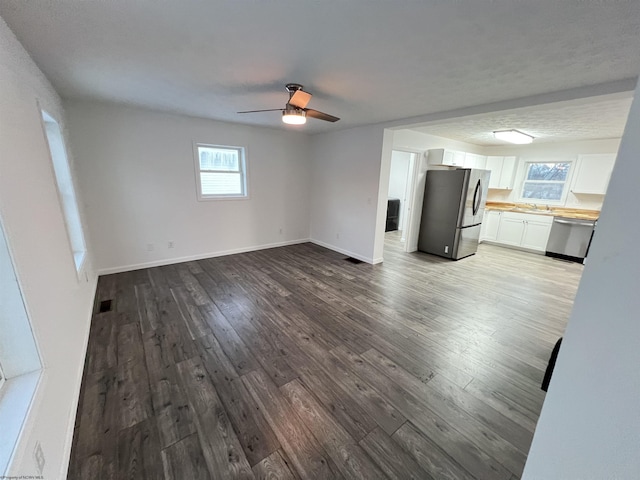 unfurnished living room with hardwood / wood-style flooring, sink, and ceiling fan