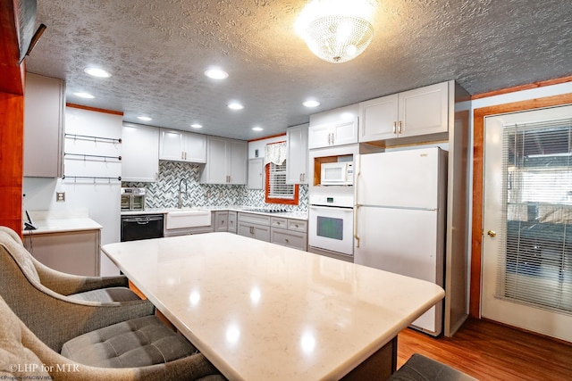 kitchen featuring light hardwood / wood-style floors, black appliances, decorative backsplash, sink, and a textured ceiling