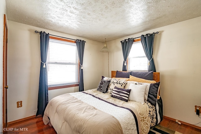 bedroom with dark hardwood / wood-style floors and a textured ceiling