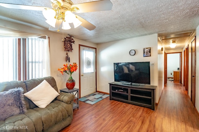 living room with ceiling fan, wood-type flooring, and a textured ceiling