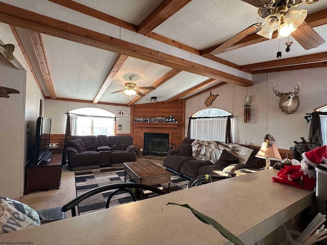 carpeted living room with a textured ceiling, wooden walls, and beamed ceiling