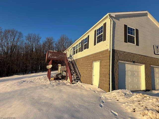 view of snow covered exterior featuring a garage and a deck