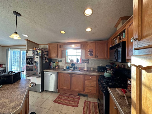 kitchen featuring light tile patterned floors, black appliances, decorative light fixtures, crown molding, and sink