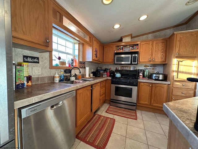 kitchen featuring a textured ceiling, appliances with stainless steel finishes, sink, ornamental molding, and light tile patterned flooring