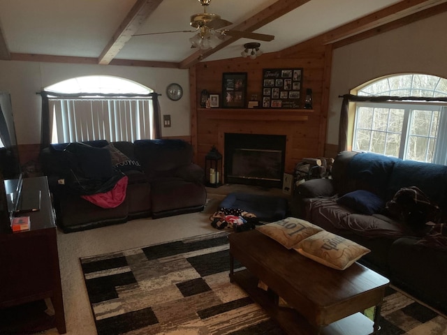 carpeted living room featuring ceiling fan, vaulted ceiling with beams, and wooden walls