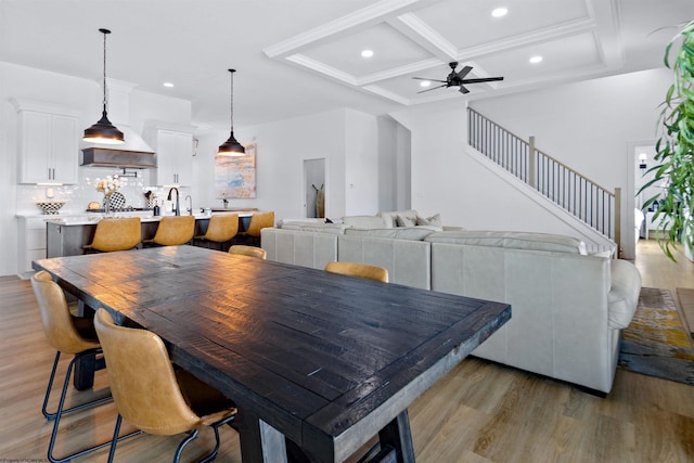 dining area with ceiling fan, light hardwood / wood-style floors, beamed ceiling, and coffered ceiling