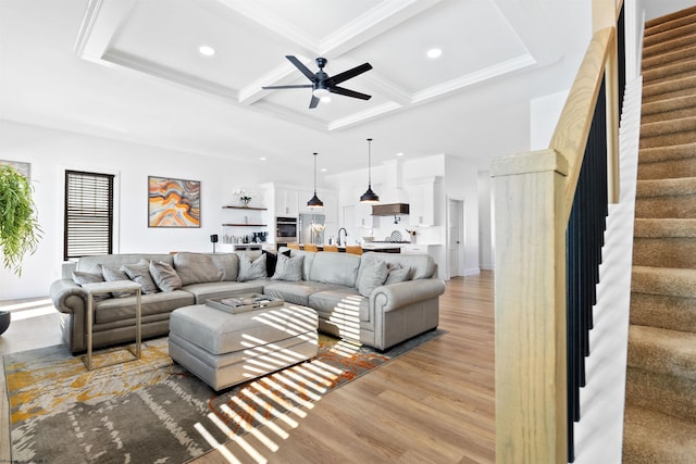 living room featuring wood-type flooring, beamed ceiling, ceiling fan, crown molding, and coffered ceiling