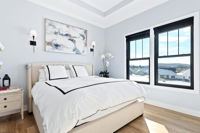 bedroom with multiple windows, ornamental molding, and light wood-type flooring