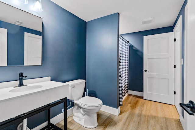 bathroom featuring toilet, walk in shower, hardwood / wood-style flooring, and vanity