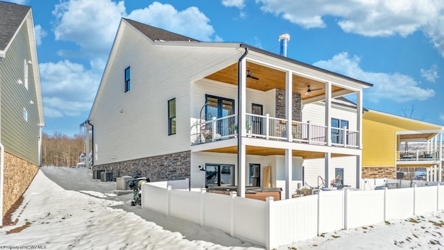 snow covered rear of property featuring a balcony, a porch, ceiling fan, and central air condition unit