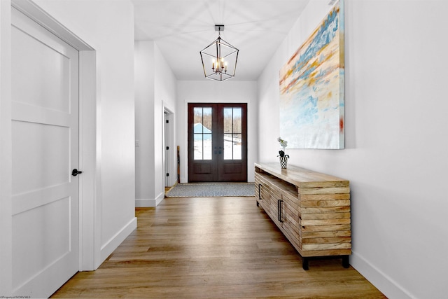 doorway to outside featuring light wood-type flooring, a chandelier, and french doors