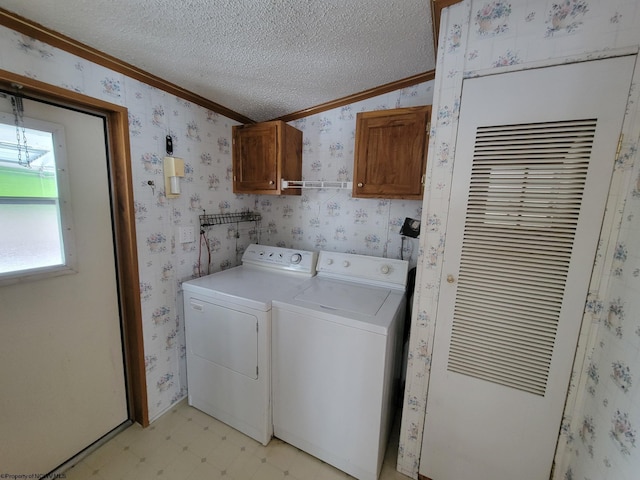 washroom with cabinets, a textured ceiling, crown molding, and washing machine and clothes dryer