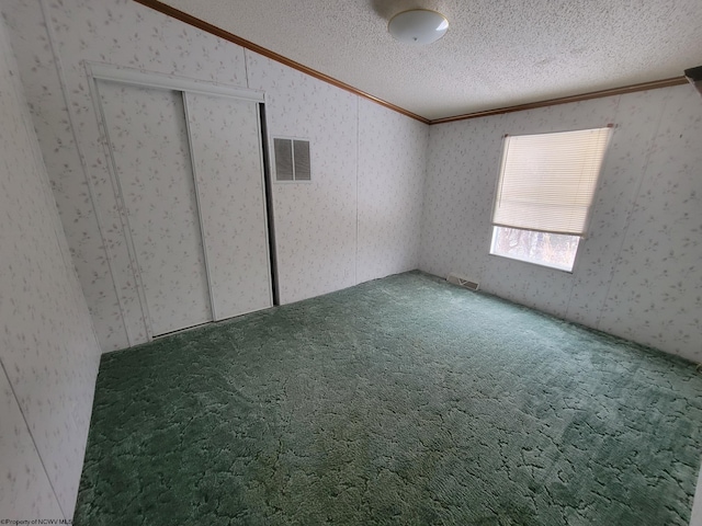 unfurnished bedroom featuring ornamental molding, carpet, a closet, and a textured ceiling