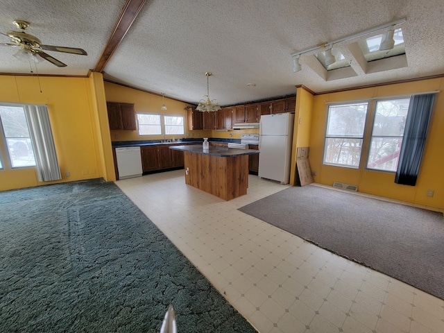 kitchen featuring decorative light fixtures, a center island, white appliances, a textured ceiling, and ceiling fan with notable chandelier