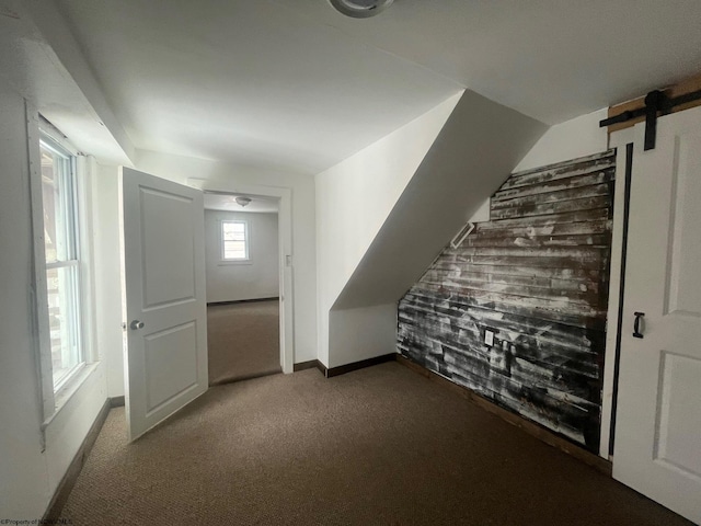 additional living space with light carpet and a barn door