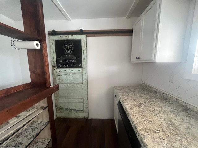 kitchen featuring a barn door, backsplash, dark hardwood / wood-style floors, white cabinetry, and light stone countertops