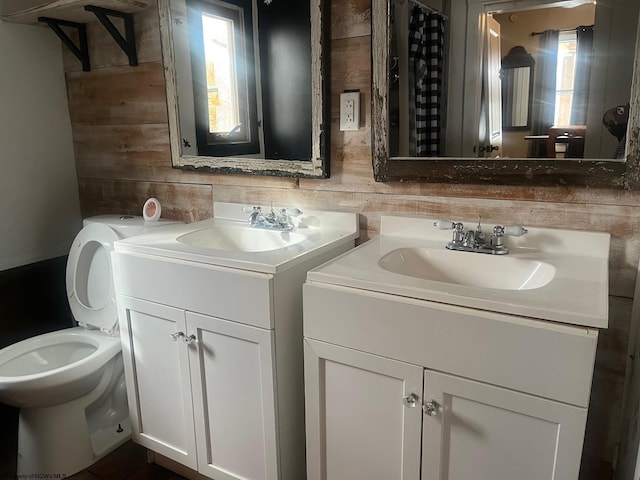 bathroom with toilet, vanity, and wood walls