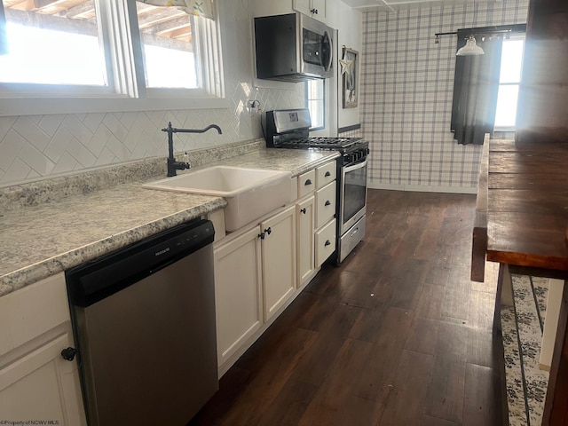 kitchen featuring white cabinets, appliances with stainless steel finishes, dark hardwood / wood-style flooring, tasteful backsplash, and sink