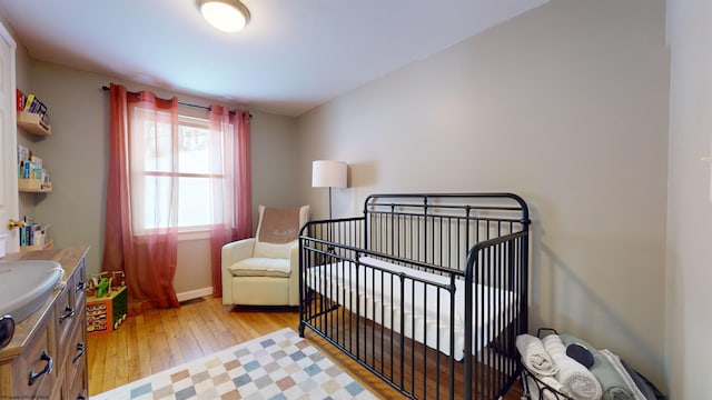 bedroom featuring a nursery area and light hardwood / wood-style flooring