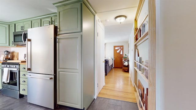 kitchen with stainless steel appliances, hardwood / wood-style flooring, and green cabinetry