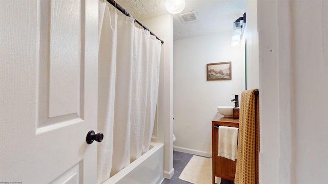 bathroom featuring a textured ceiling, shower / bath combo, and vanity