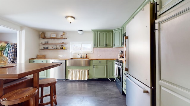 kitchen with green cabinets, appliances with stainless steel finishes, decorative backsplash, and sink