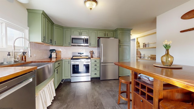 kitchen featuring tasteful backsplash, green cabinetry, butcher block counters, and stainless steel appliances