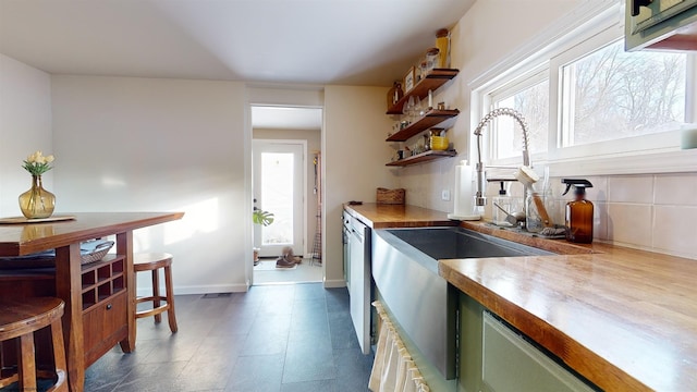 kitchen with green cabinets, a wealth of natural light, stainless steel dishwasher, and wooden counters