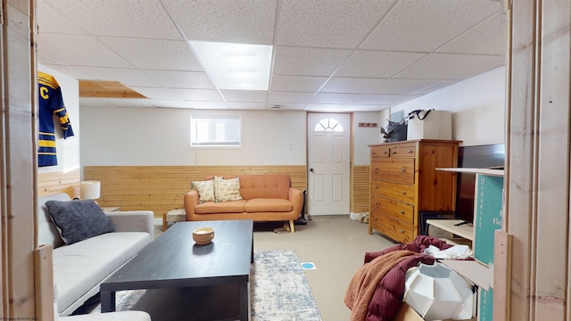 living room featuring a paneled ceiling and wood walls