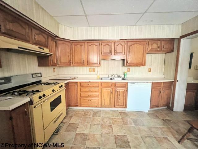 kitchen featuring a drop ceiling, sink, and white appliances