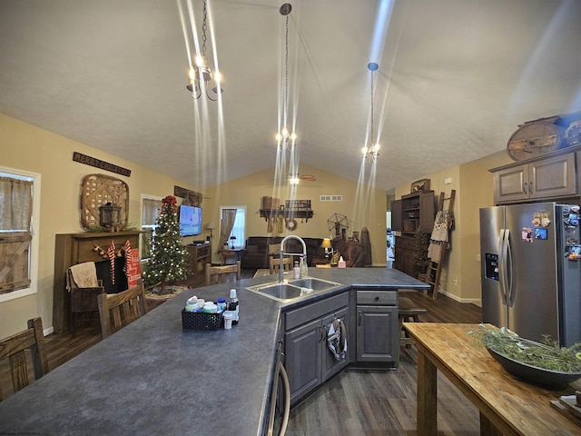 kitchen featuring vaulted ceiling, sink, hanging light fixtures, stainless steel fridge with ice dispenser, and dark hardwood / wood-style flooring