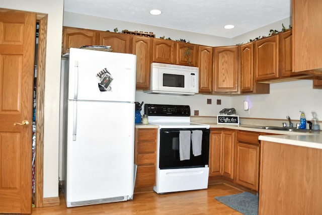 kitchen featuring sink, white appliances, and light hardwood / wood-style floors