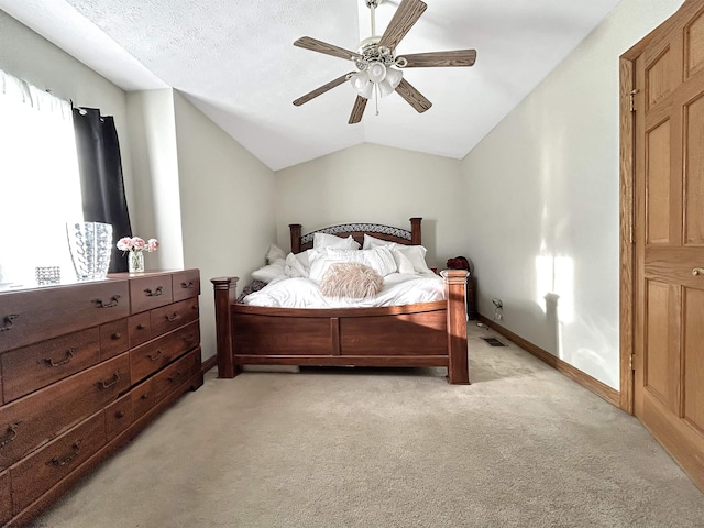 bedroom featuring ceiling fan, light colored carpet, vaulted ceiling, and a textured ceiling