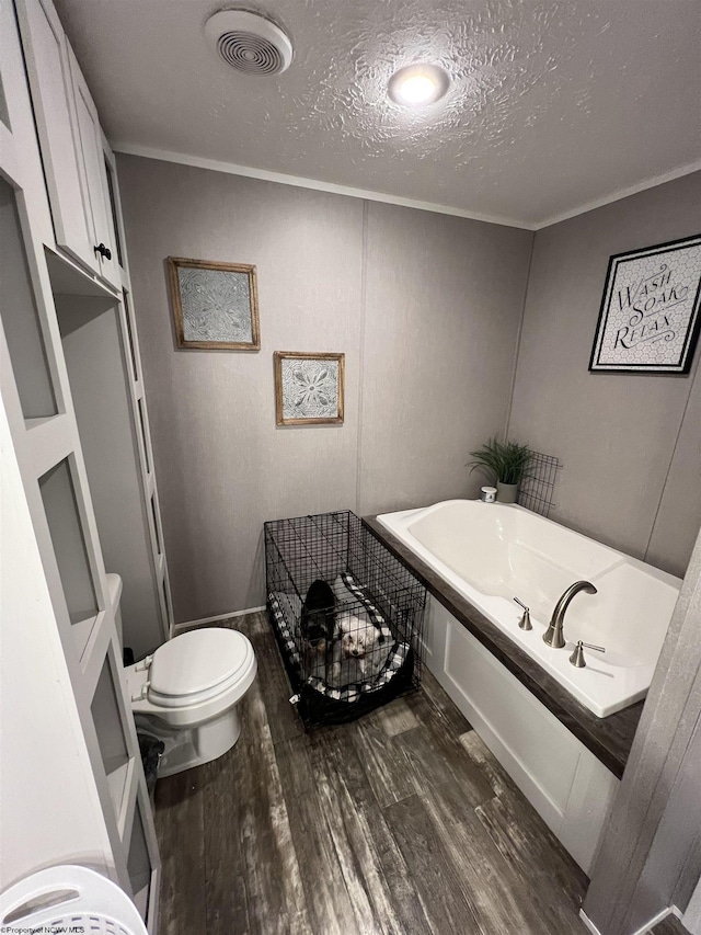 bathroom featuring visible vents, toilet, ornamental molding, a textured ceiling, and wood finished floors