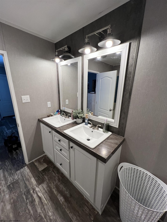 full bath featuring double vanity, a textured wall, a sink, and wood finished floors