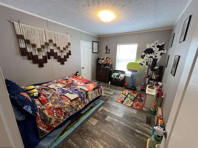 bedroom with crown molding, a textured ceiling, and wood finished floors