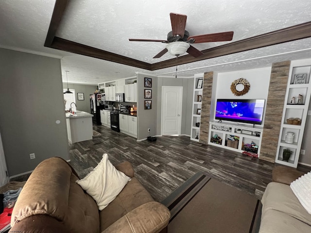 living area featuring a textured ceiling, built in shelves, dark wood-type flooring, baseboards, and ornamental molding