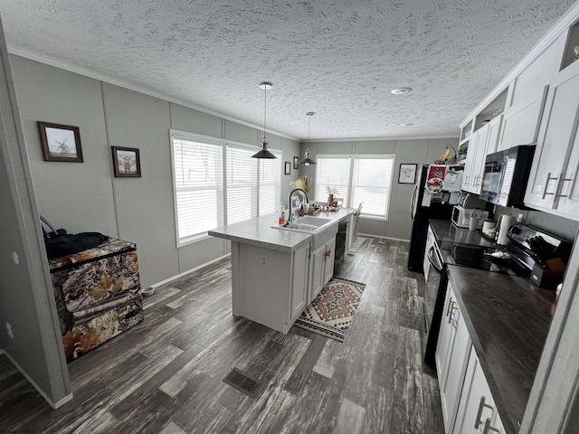 kitchen featuring a kitchen island with sink, white cabinets, hanging light fixtures, ornamental molding, and black appliances