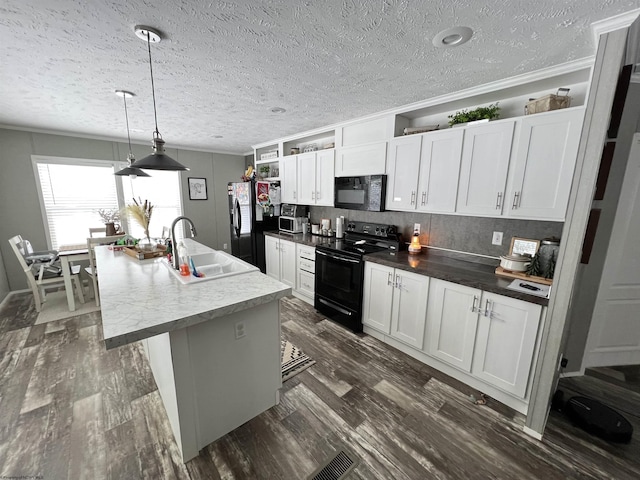 kitchen featuring a kitchen island with sink, black appliances, white cabinetry, pendant lighting, and a sink