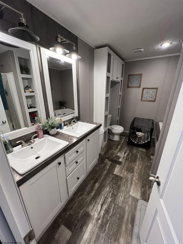 bathroom featuring double vanity, a sink, toilet, and wood finished floors