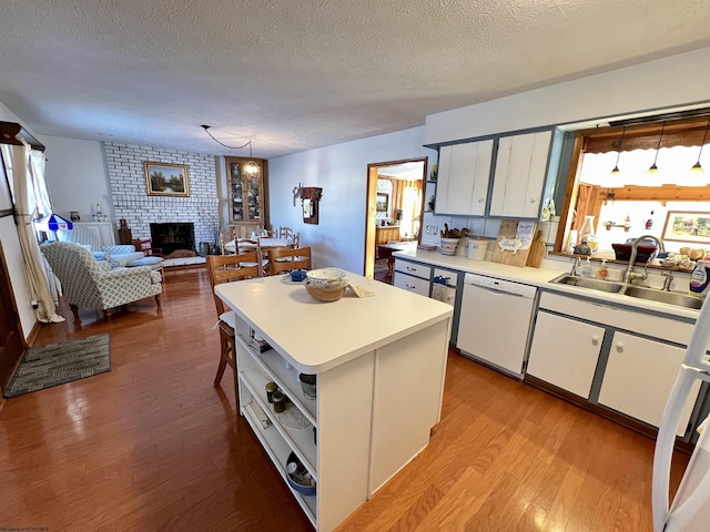 kitchen featuring pendant lighting, dishwasher, sink, white cabinetry, and a kitchen island