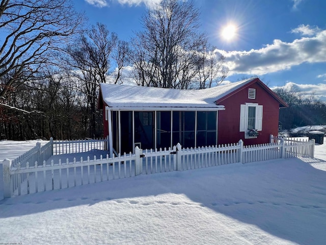 snow covered property featuring a sunroom